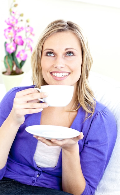 Donna brillante godendo il suo caffè seduti sul divano