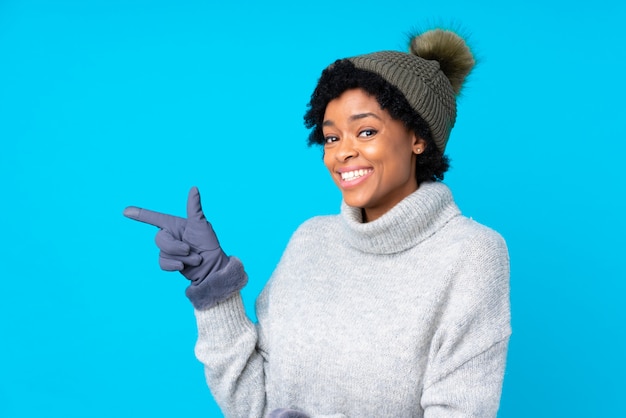 donna bruna con cappello invernale su sfondo blu isolato