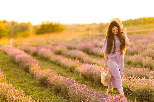 Donna bruna con cestino da picnic che trascorre i fine settimana all'aperto godendosi la bella natura dell'aria fresca