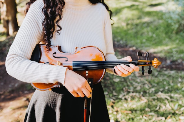 donna bruna irriconoscibile che tiene un violino fuori nel bosco