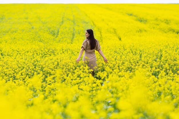 donna cammina correre lungo campo giallo colza