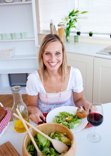 Donna carina che mangia un&#39;insalata in cucina