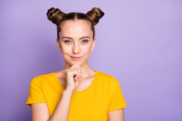 Donna carina con topknots in posa contro il muro viola