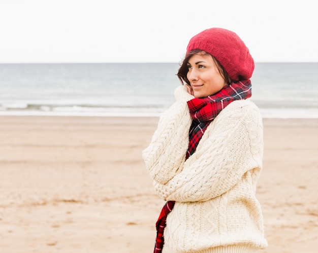 Donna carina in vestiti caldi alla moda in spiaggia