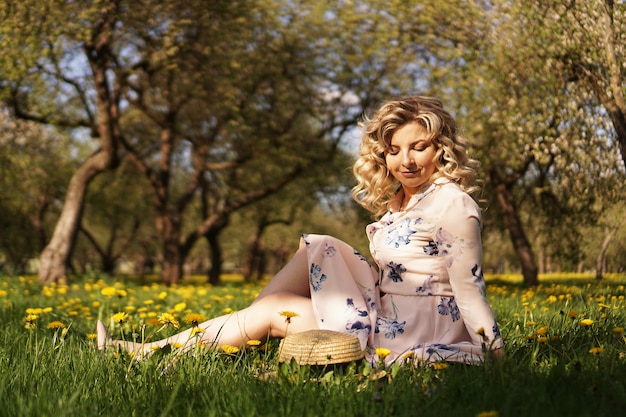 Donna carina resto nel parco estivo verde con denti di Leone