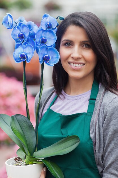 Donna castana che tiene un fiore blu che lavora nel Garden Center