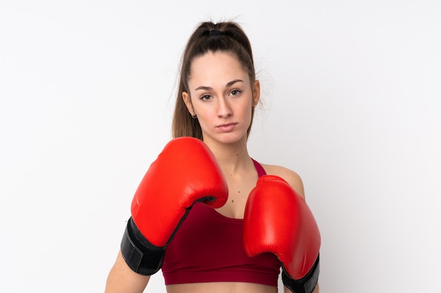 Donna castana di sport giovane sopra la parete bianca isolata con guantoni da boxe