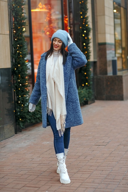 Donna castana piacevole in cappotto che cammina alla città nell'inverno