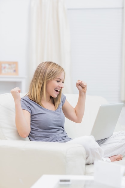 Donna casuale emozionante con il computer portatile a casa