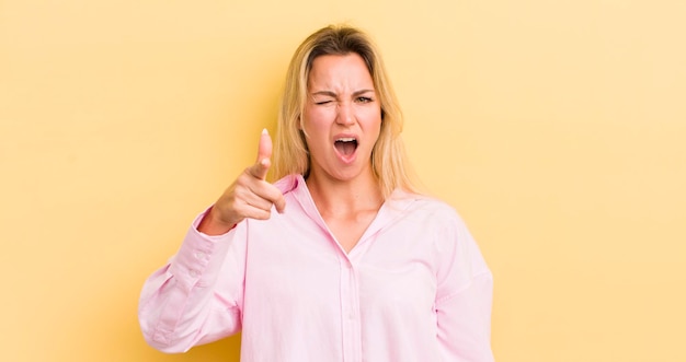 Donna caucasica bionda che punta alla telecamera con un'espressione aggressiva arrabbiata che sembra un capo pazzo furioso