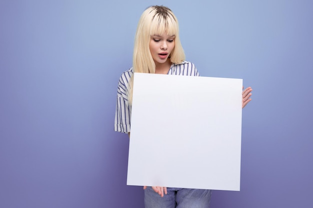 Donna caucasica bionda manager in camicia a righe con poster bianco su sfondo studio con copia