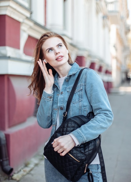 Donna caucasica carina che indossa le cuffie wireless in città