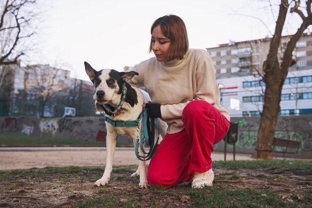 Donna caucasica che abbraccia il suo cane durante una passeggiata nel parco