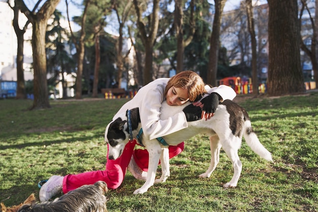 Donna caucasica che abbraccia il suo cane durante una passeggiata nel parco