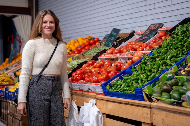 Donna caucasica che compra verdure e verdure nella vita vegetariana del negozio di alimentari