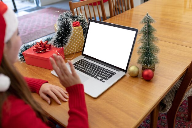 Donna caucasica che indossa un cappello da Babbo Natale con videochiamata sul laptop con spazio per la copia nel periodo natalizio. natale, festività e tecnologia della comunicazione a casa.