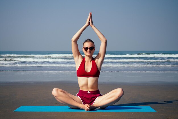 Donna caucasica che pratica yoga in riva al mare