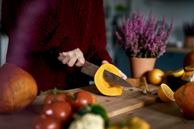 Donna caucasica che prepara la zucca per la zuppa in cucina