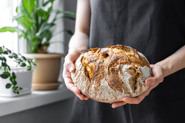 Donna caucasica che tiene il pane fresco dal forno che cuoce il pane fatto in casa