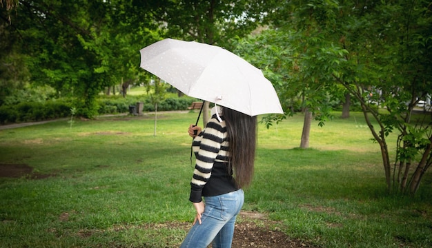 Donna caucasica che tiene ombrello nel parco