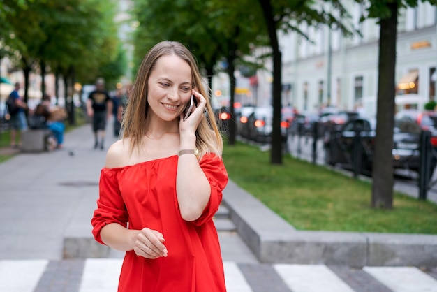 Donna caucasica con smartphone in piedi contro la strada sfocata