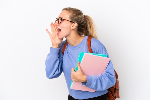 Donna caucasica del giovane studente isolata su fondo bianco che grida con la bocca spalancata al lato