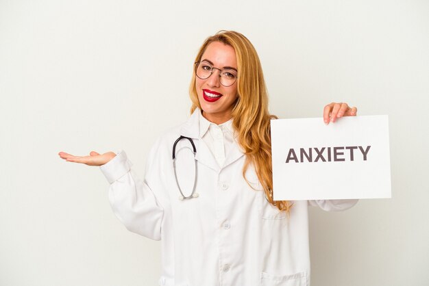 Donna caucasica del medico che tiene un cartello di ansia isolato su fondo bianco che mostra uno spazio della copia su una palma e che tiene un'altra mano sulla vita.