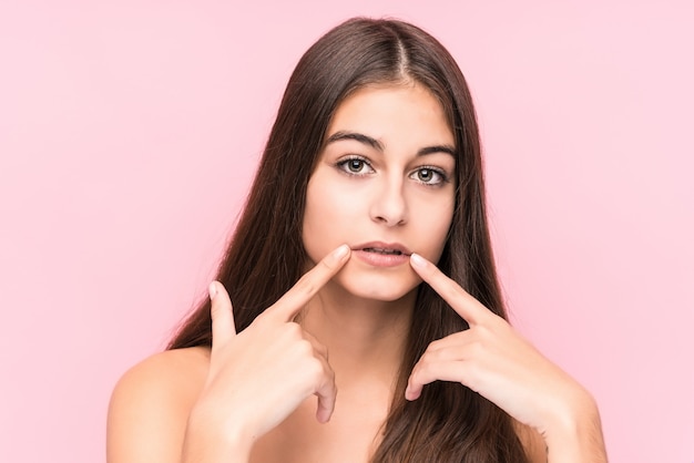 Donna caucasica di giovane bellezza contro una parete rosa