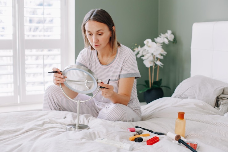 Foto donna caucasica di mezza età che si trucca al mattino, giovane donna seduta a letto a casa