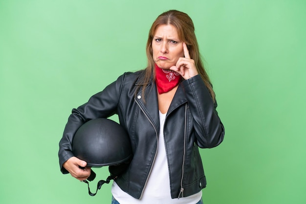 Donna caucasica di mezza età con un casco da motociclista su sfondo isolato pensando un'idea