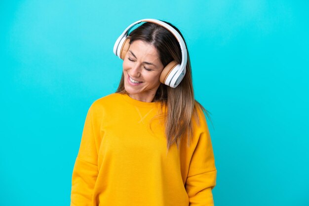 Donna caucasica di mezza età isolata su sfondo blu ascoltando musica