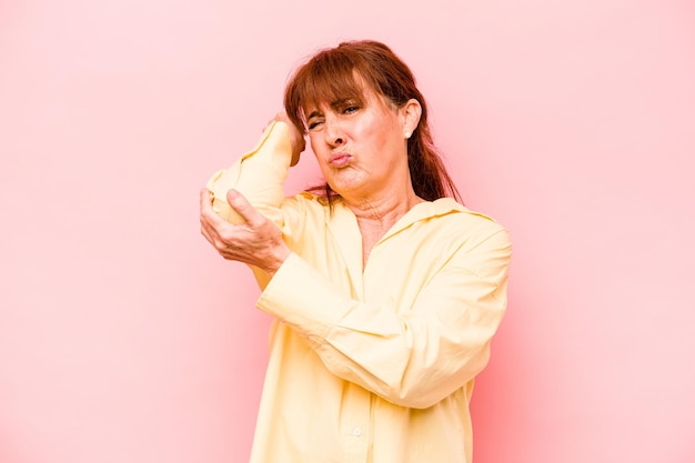 Donna caucasica di mezza età isolata su sfondo rosa con dolore al collo dovuto allo stress che massaggia e lo tocca con la mano