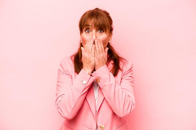 Donna caucasica di mezza età isolata su sfondo rosa scioccata che copre la bocca con le mani