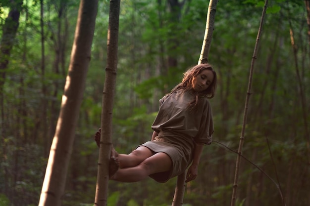 Donna caucasica in abito seduto tra gli alberi nella foresta