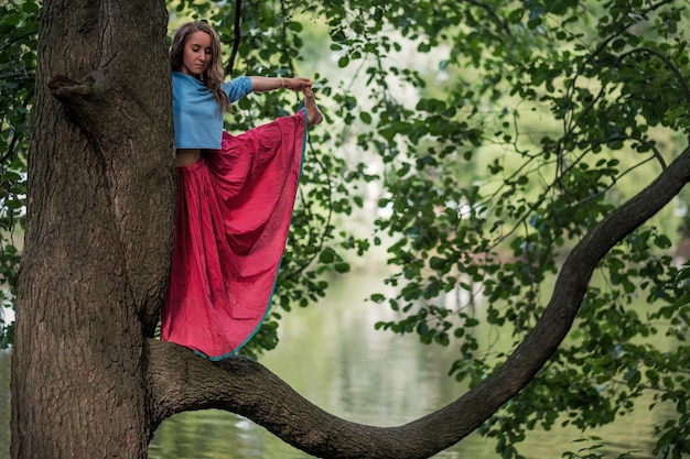 Donna caucasica in piedi in equilibrio yoga Utthita Hasta Padangusthasana posa Lei tiene trank di albero