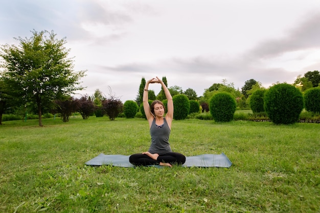 Donna caucasica, istruttrice di yoga, che fa allungamento laterale, piega laterale della colonna vertebrale seduta, piega laterale seduta.