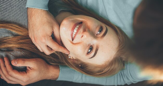 Donna caucasica lentigginosa con i capelli rossi sdraiata sulle ginocchia degli amanti e guardandolo con amore