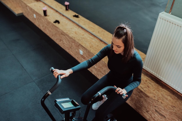 Donna caucasica seria in abbigliamento sportivo seduto su una cyclette pronta per raggiungere buoni risultati in cardiom.