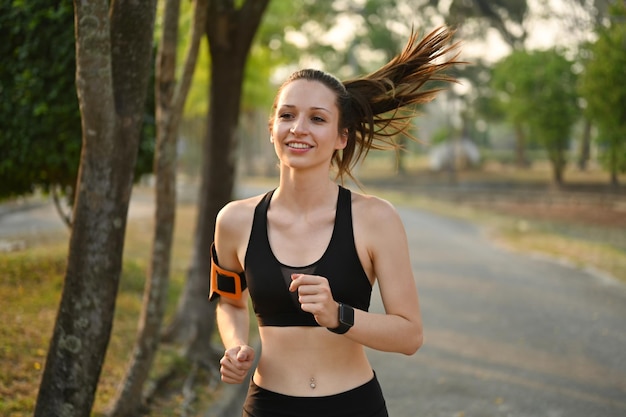 Donna caucasica sportiva attiva che indossa abbigliamento sportivo che fa jogging su strada nel parco estivo all'alba Concetto di stile di vita sano e attivo