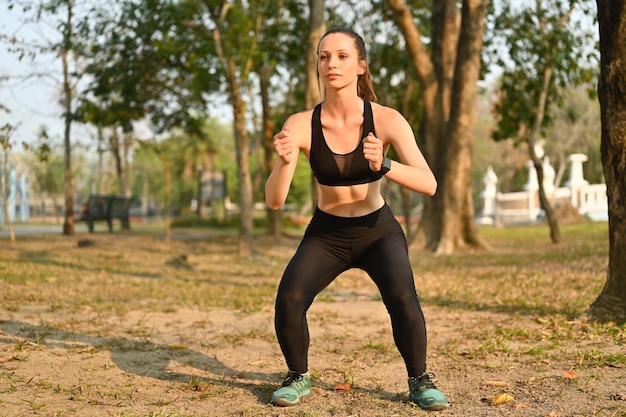 Donna caucasica sportiva in abbigliamento sportivo che si allena al mattino facendo esercizio di squat