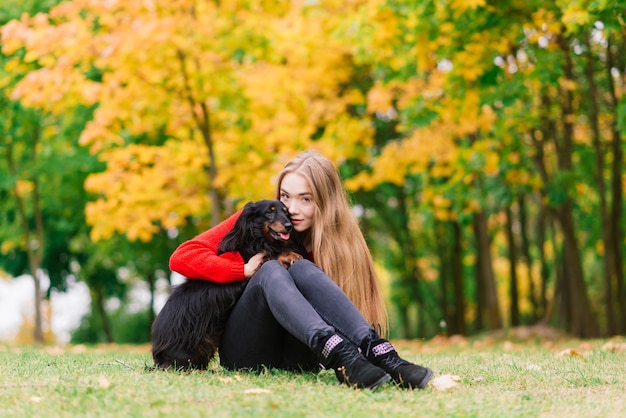 Donna che abbraccia cane nel parco estivo