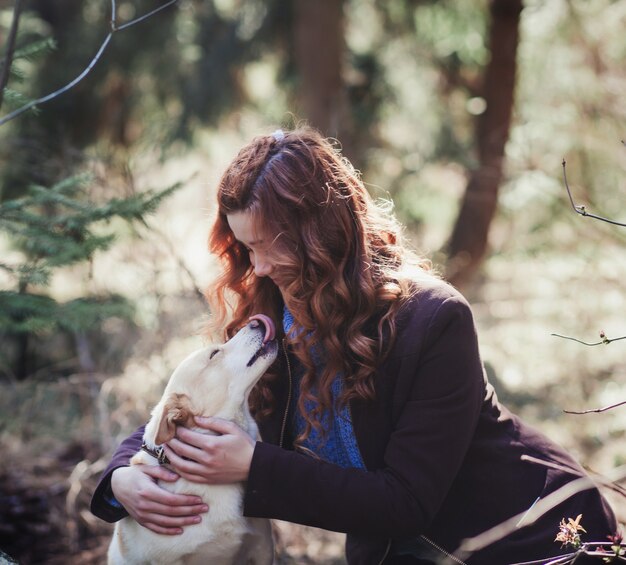 Donna che abbraccia un cane nella foresta