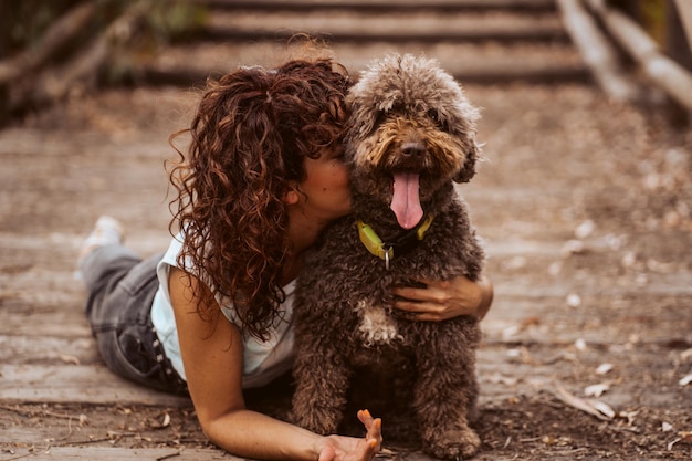 Donna che abbraccia un cane sdraiato sulla strada
