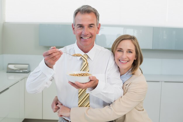 Donna che abbraccia uomo mentre fa colazione in cucina