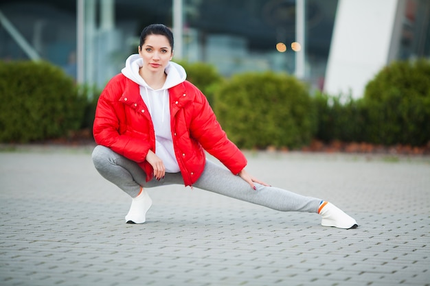 Donna che allunga corpo, facendo esercizi sulla strada