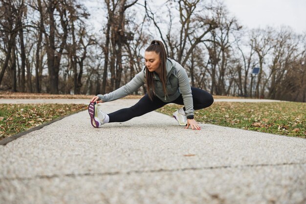 Donna che allunga le gambe sulla strada nel parco