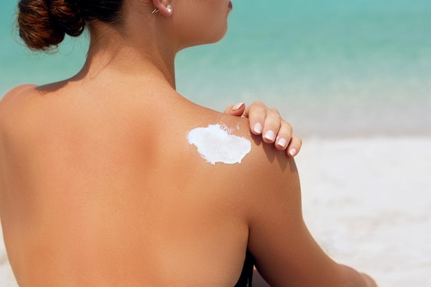 Donna che applica crema solare sulla spalla abbronzata Skincare Body Protezione solare