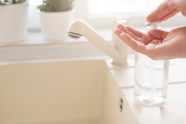 Donna che applica detersivo sulle mani vicino al lavandino della cucina a casa. Concetto di igiene durante l'epidemia di coronavirus. prevenzione del coronavirus.