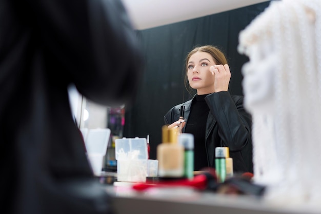 Donna che applica il trucco di base sul viso dietro le quinte