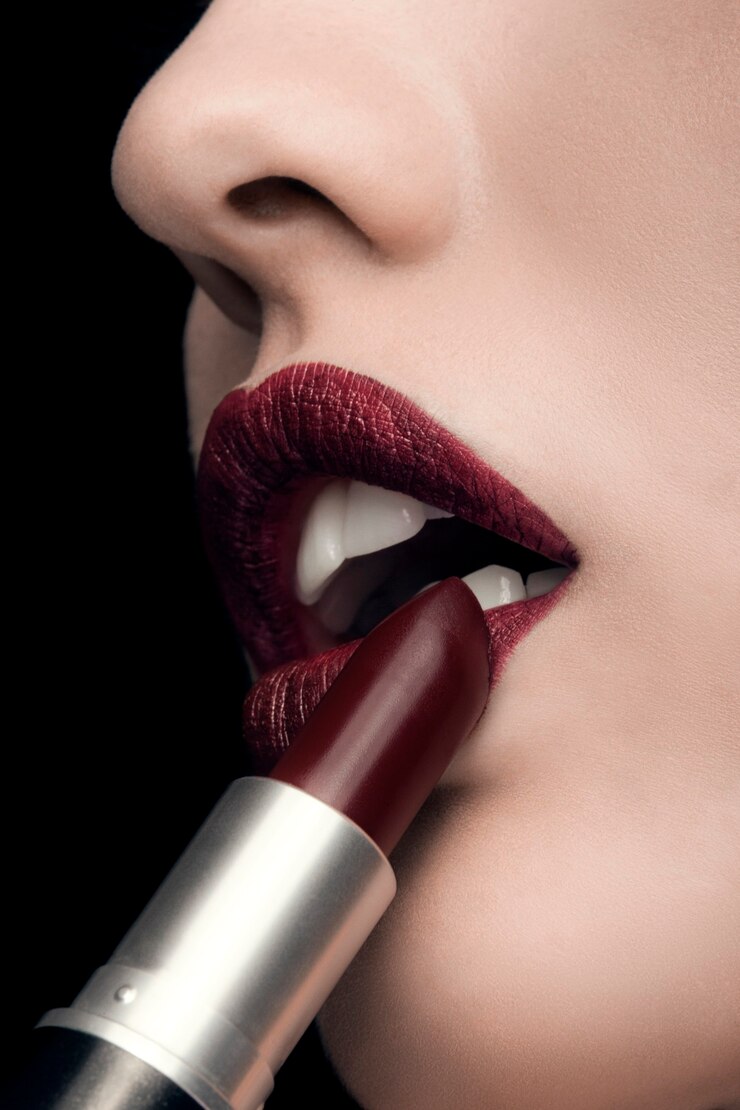Foto donna che applica rossetto rosso su sfondo nero in studio fotografico